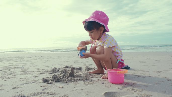 可爱的女孩在沙滩上玩沙子，玩得很开心