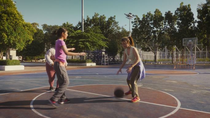 一小群年轻的亚洲女性朋友喜欢在户外球场上打篮球