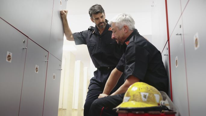 成熟的男性消防员在更衣室与队友交谈