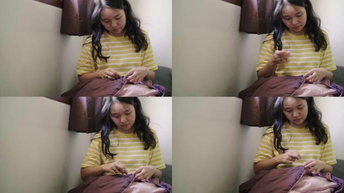 一位年轻的亚洲女子用手缝制衣服。