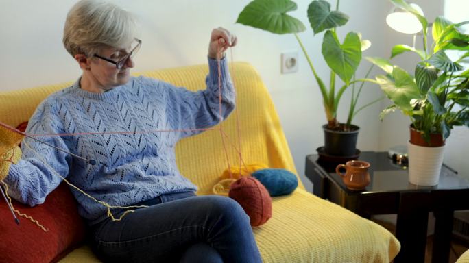 一位退休妇女在起居室里编织着一把雨拍