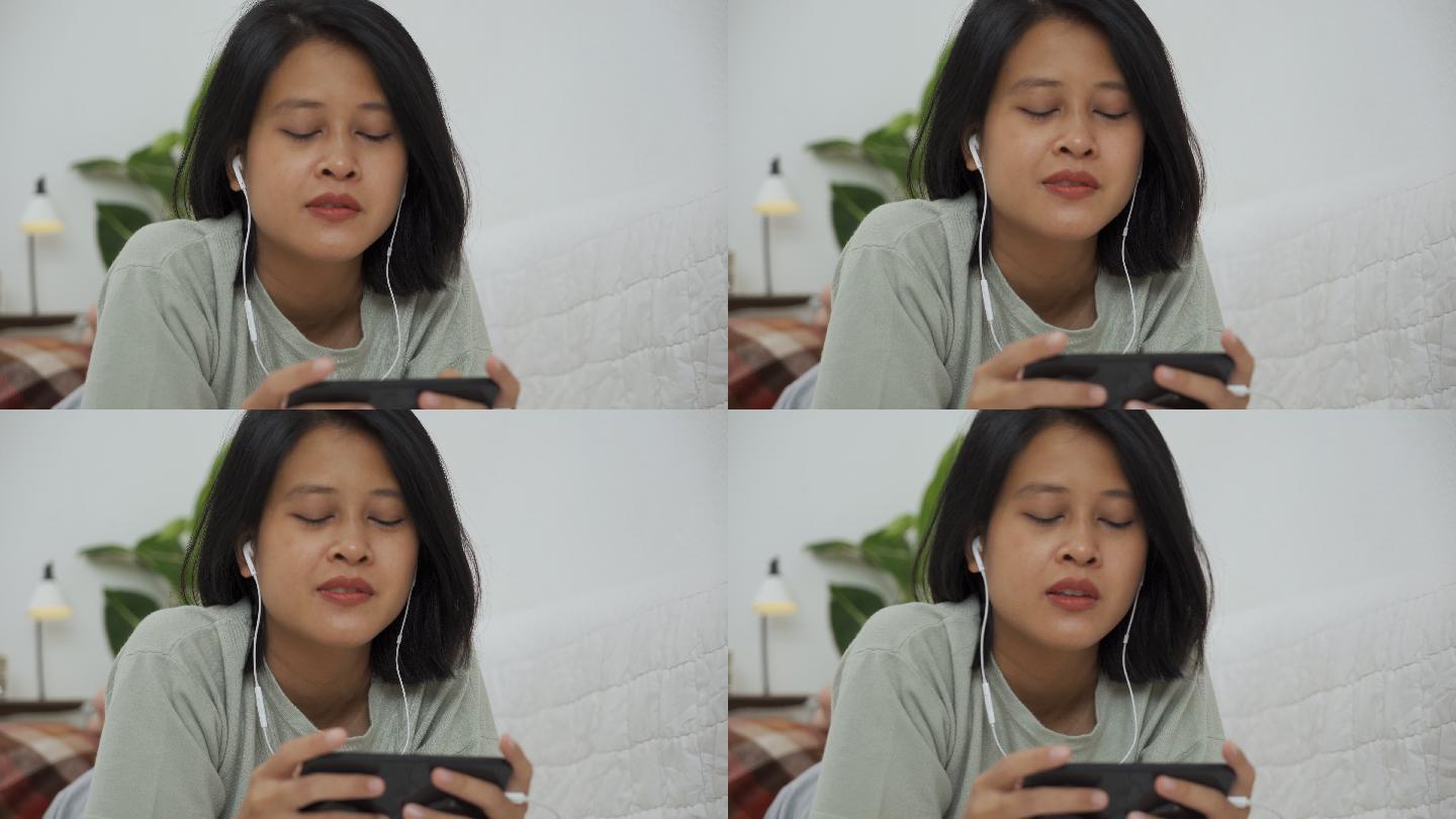 亚洲女性戴着耳机在智能手机上玩游戏