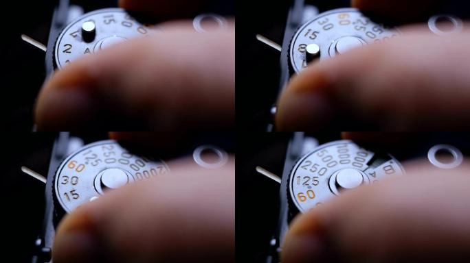 一台老式单反胶片相机的特写细节和手指调节曝光速度刻度盘时发出的咔嗒声