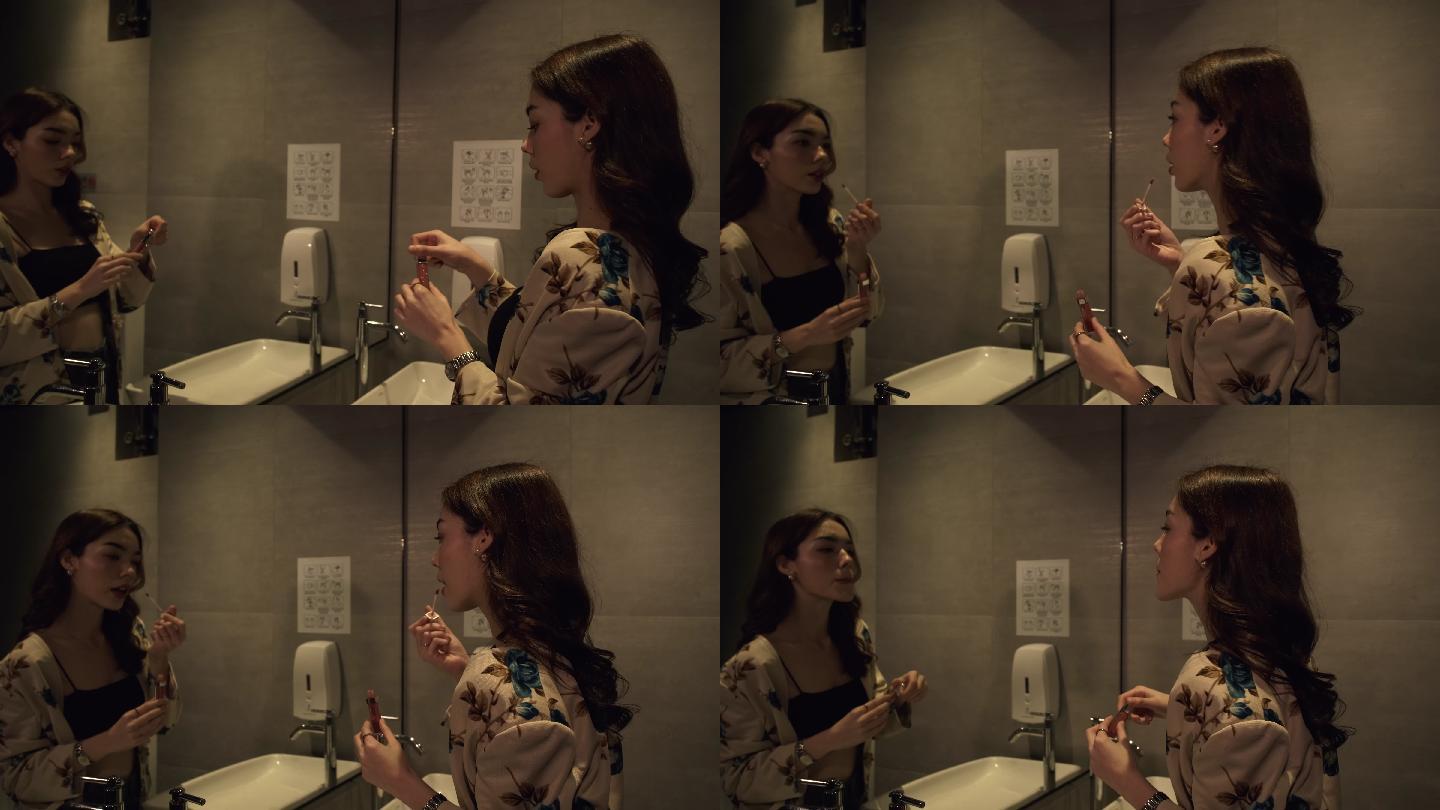 女性在卫生间镜子前涂上口红。
