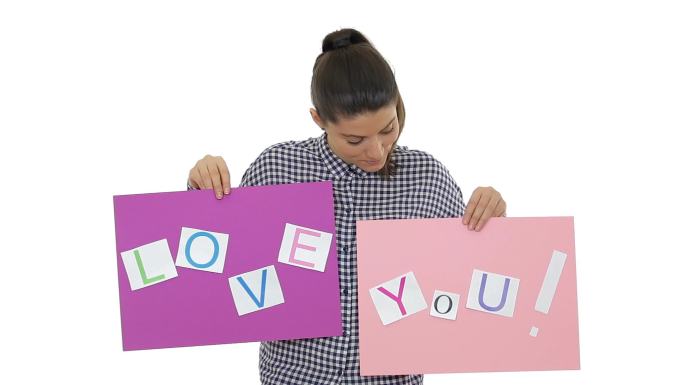 美丽的年轻女子用标语牌说“爱你”。