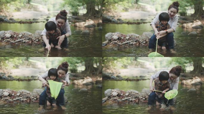 亚洲家庭和两个儿子在河里用渔网捕鱼