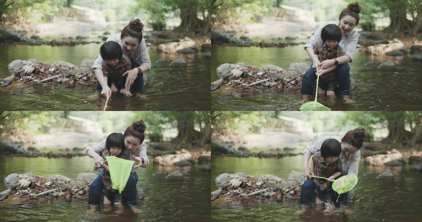 亚洲家庭和两个儿子在河里用渔网捕鱼