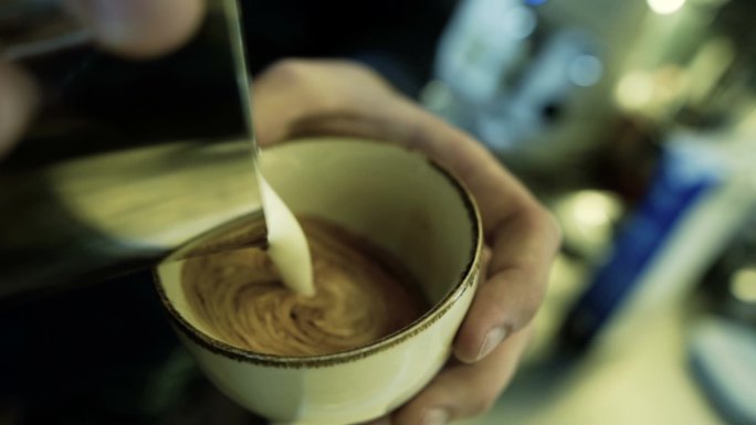 专业咖啡师在杯子里制作倒流牛奶拿铁艺术图案。股票视频