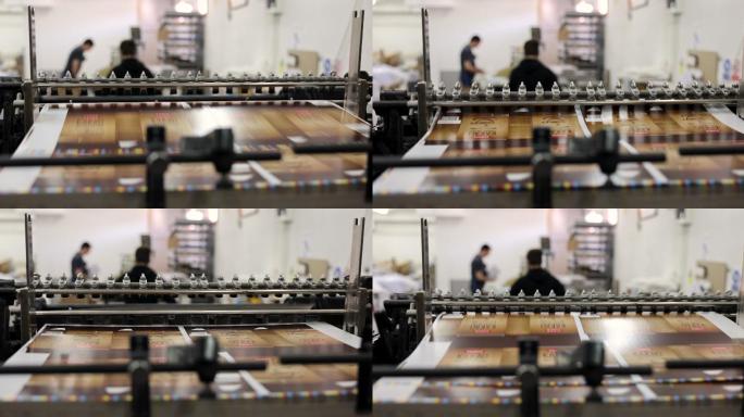 一台自动化机器的特写镜头，在印刷厂堆叠印刷介质，而工人在后台工作