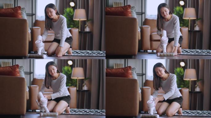 穿着T恤和短裤的亚洲年轻美女正在家里明亮舒适的房间里用吸尘器清洁地毯。她使用现代无绳吸尘器。电器和趣