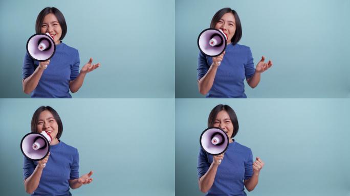 快乐的亚洲女人用扩音器在蓝色背景上做出孤立的叫喊手势。4K视频