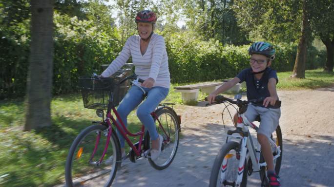 男孩和奶奶在阳光公园里骑自行车