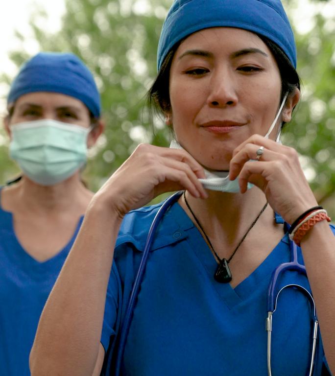 微笑的亚裔和白种人医护人员戴着防护面罩