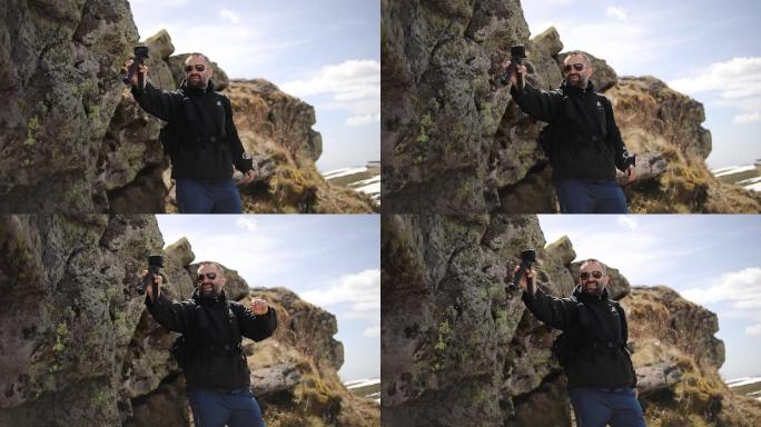 这位徒步旅行者走上山，用他的gopro相机拍摄，为他的viode博客制作视频。