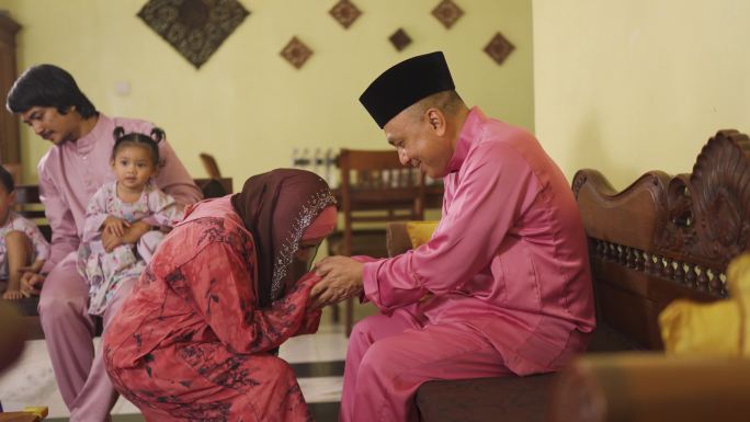 在客厅举行的Aidilfitri庆典上，身着传统服装的哈里·拉亚马来穆斯林祖母向丈夫道歉