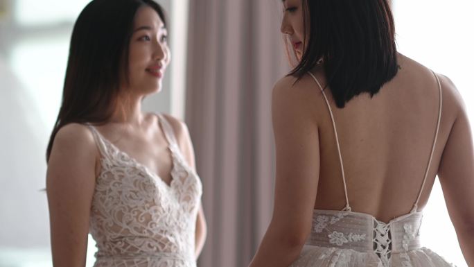 慢镜头2：穿着婚纱的美女在婚纱店摆姿势，在白色背景下微笑