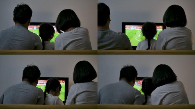 一个亚洲家庭坐在沙发上看电视足球比赛，一起欢呼，为胜利而高兴。