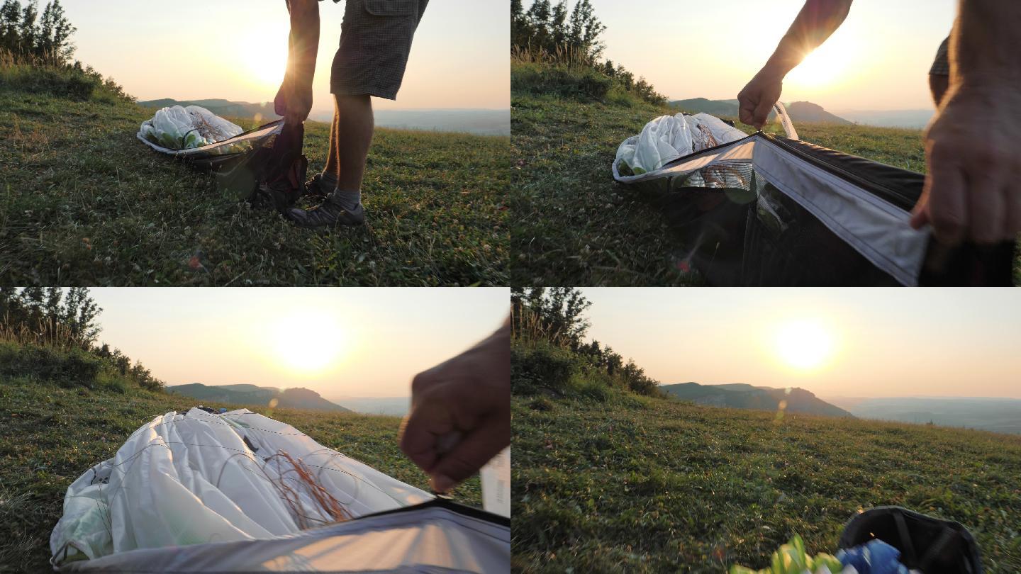 日落时，一个人的手慢慢地合上滑翔伞的机翼