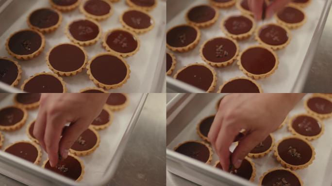 特写：面包师在巧克力馅饼的顶部添加巧克力片
