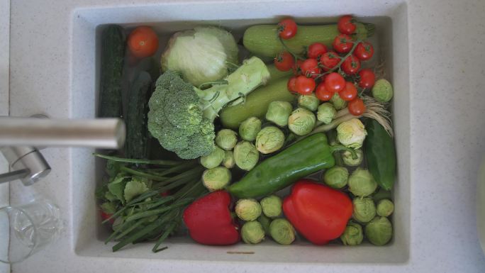 厨房水槽里装满了浸泡在水中的新鲜蔬菜