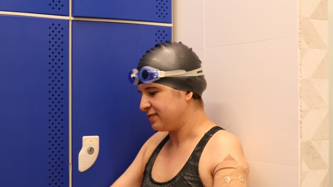 独臂女游泳运动员坐在更衣室的肖像