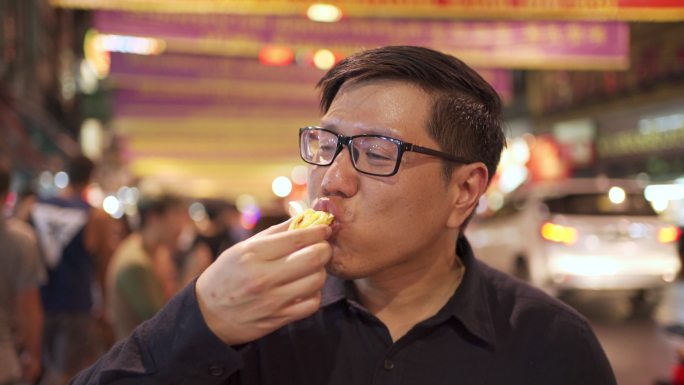 泰国曼谷Yaowarat street food Road街上的亚洲男人吃蛋挞