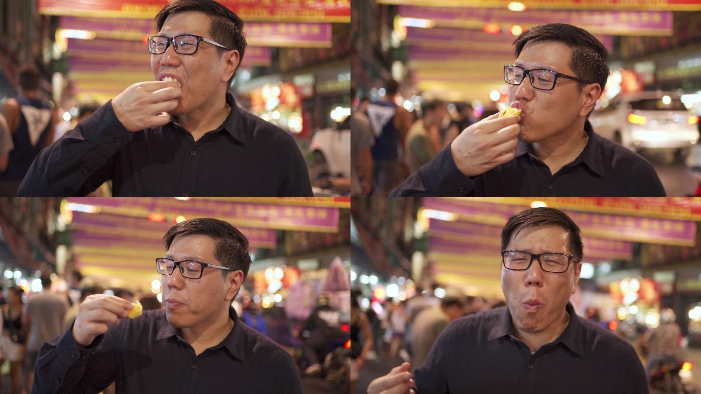 泰国曼谷Yaowarat street food Road街上的亚洲男人吃蛋挞