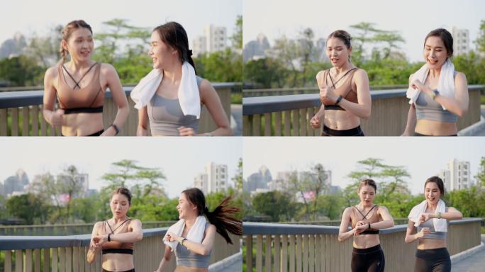 两位亚洲美丽的中年女性朋友穿着运动装，肌肉发达，早上在市中心附近公园花园的人行桥上，一起积极慢跑，用