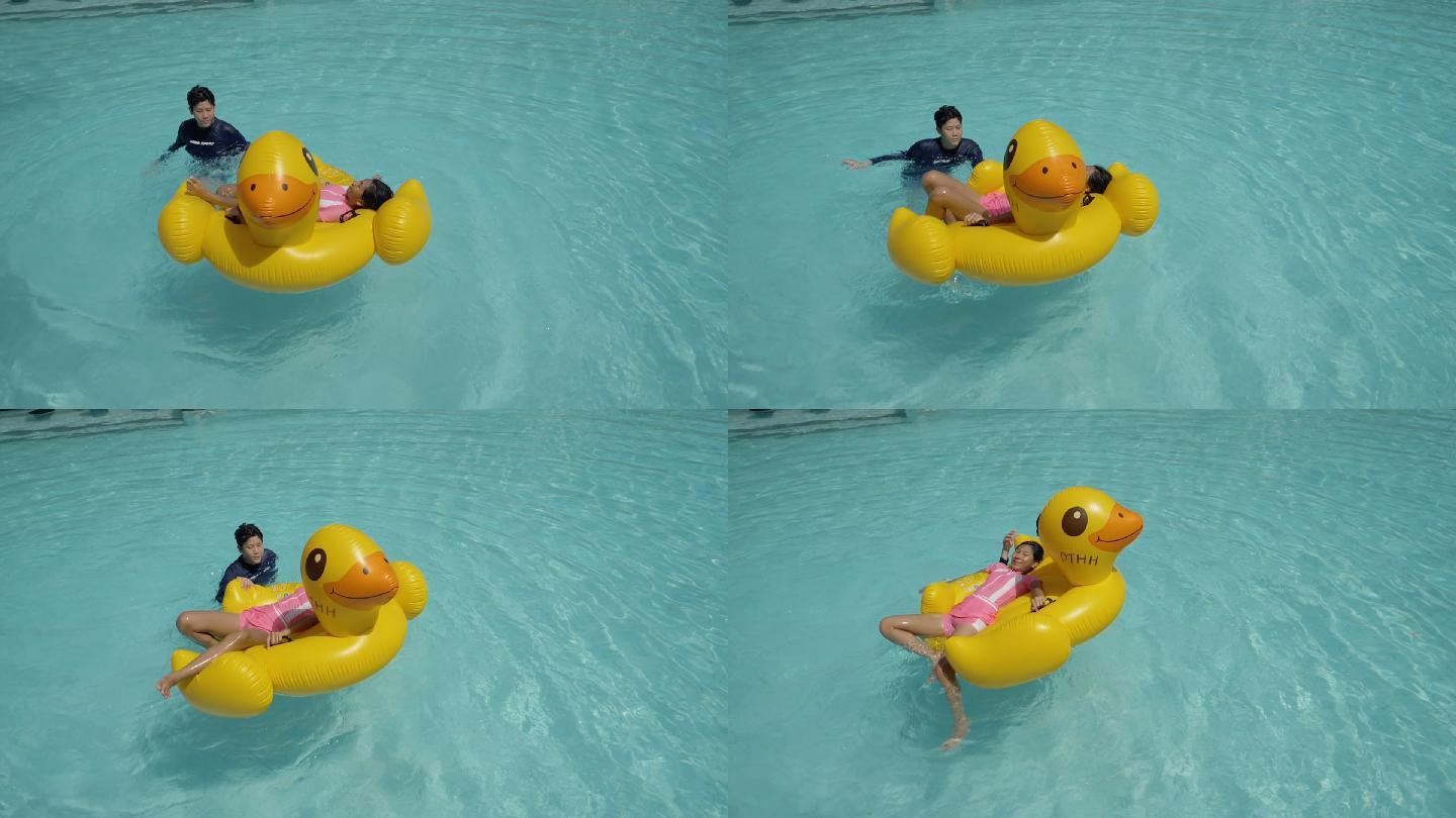 快乐的亚洲孩子和家人在酒店或度假村度假时，一起在游泳池里玩黄鸭子橡皮筏，生活方式理念。