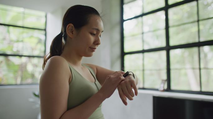 运动女性在家使用智能手表