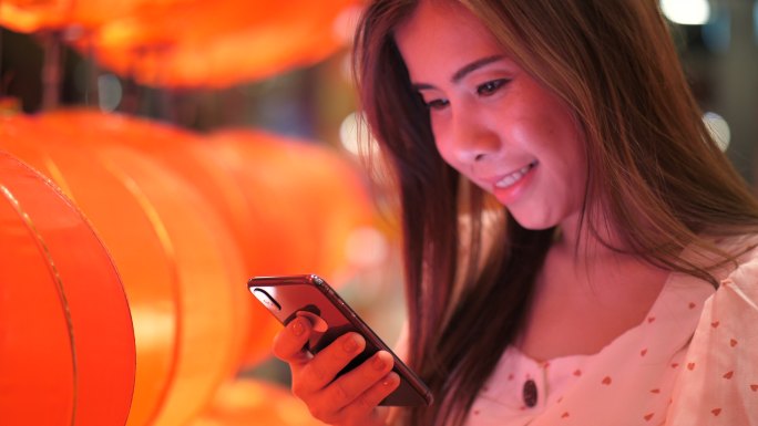 春节期间使用手机美女看手机灯笼下的女人