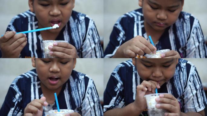 男孩在玻璃杯里吃鲜奶油