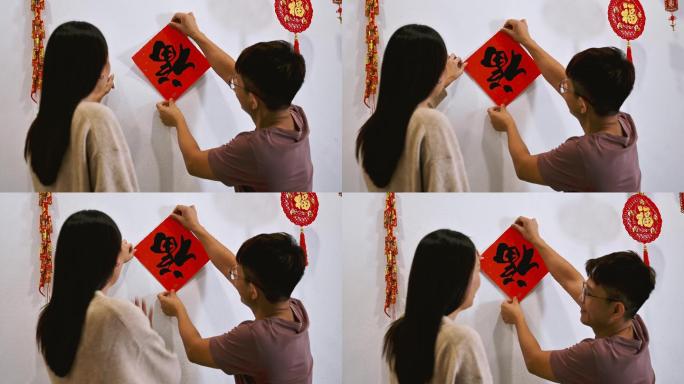 一对亚裔华人夫妇正在装修房子，并为即将到来的中国新年题词贴上中国对联，致以最美好的祝愿