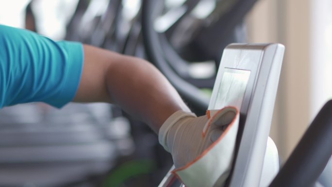 在健身房的运动设备屏幕上对表面进行病毒消毒。