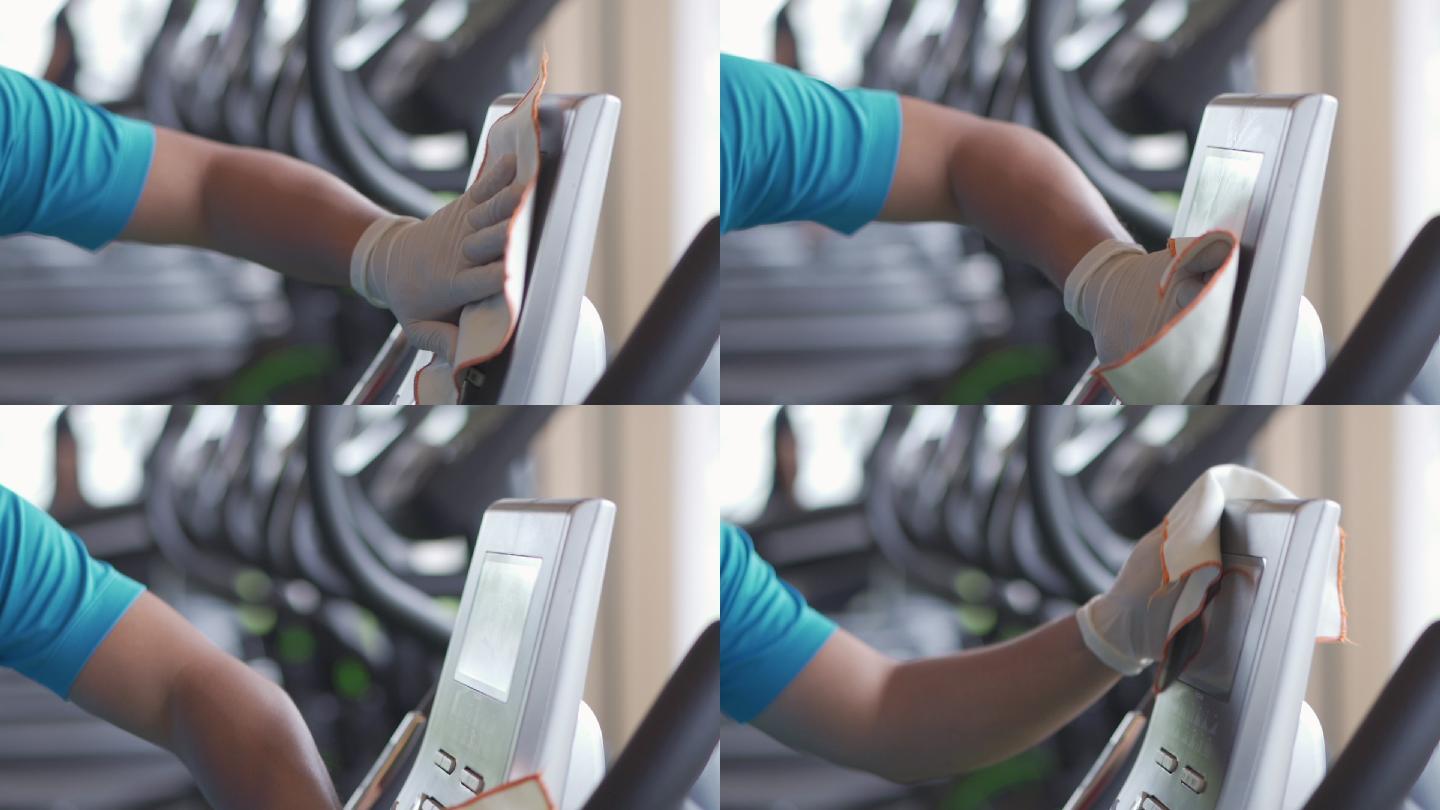 在健身房的运动设备屏幕上对表面进行病毒消毒。