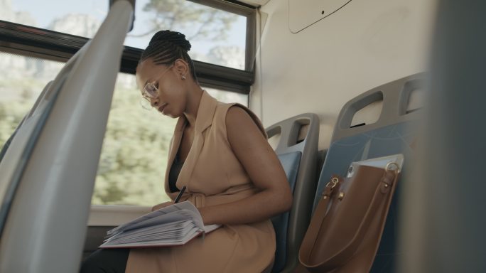 一名年轻女商人乘公共汽车旅行时在笔记本上写字的4k视频片段