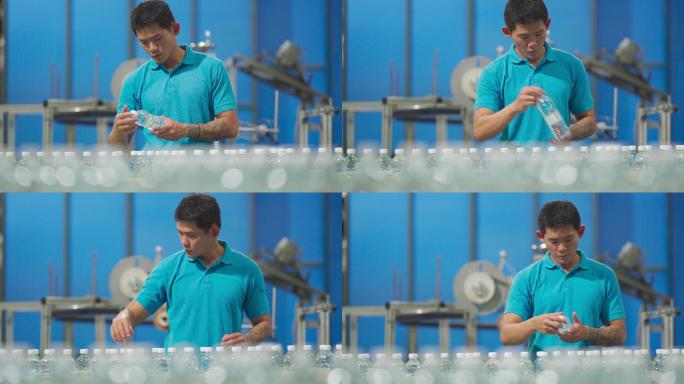 中国亚裔男性生产线工人在瓶装厂矿泉水饮用水厂检查水瓶