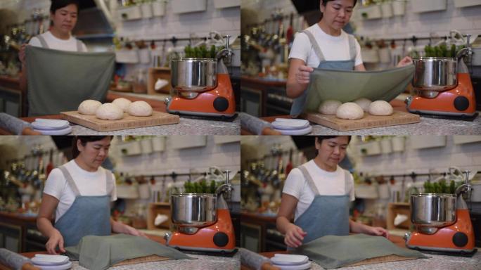 厨房里，亚洲的中国面包师妇女在面团上盖布