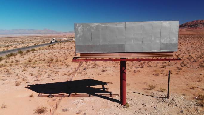 在犹他州沙漠15号州际公路旁，在晴朗的蓝天下，无人机拍摄了一个空白的废弃广告牌广告