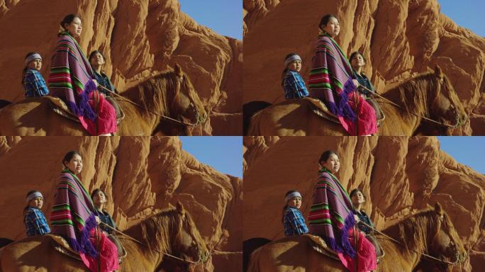 几名年轻的美国土著（纳瓦霍族）儿童穿着传统的纳瓦霍族服装，坐在马背上，看着亚利桑那州/犹他州纪念碑谷