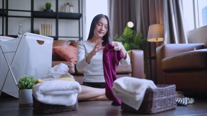 周末，一位年轻的家庭主妇在家的起居室里用手触摸一叠刚洗干净的亚麻布