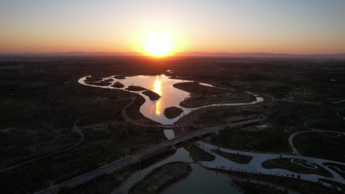 航拍中国雄安新区郊野公园夕阳与湖水