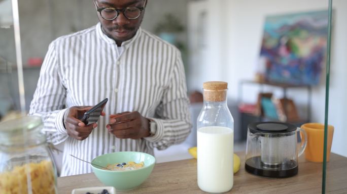 一名年轻男子为自己健康的燕麦早餐拍照，并将其发布在家中的社交媒体上