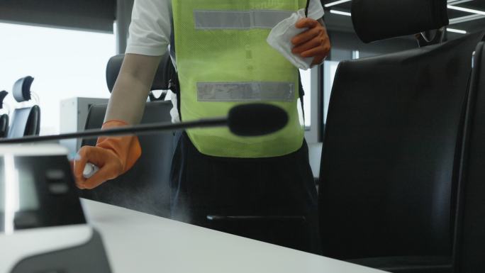 冠状病毒2019冠状病毒疾病预防保洁员用抗菌消毒剂擦拭清洁桌，以杀死表面上的冠状病毒公共会议室把手上