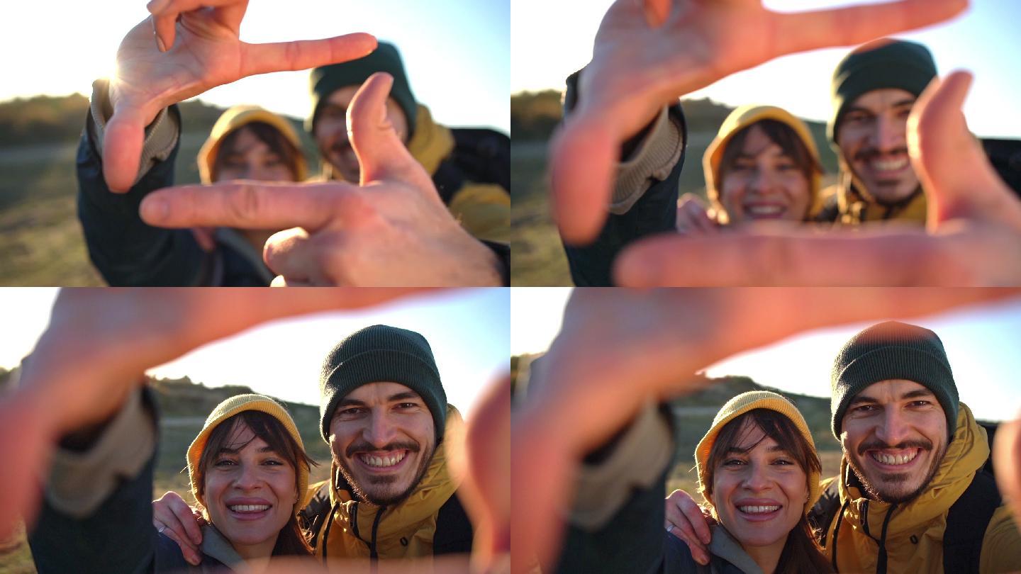 一对激动而微笑的夫妇，一边看着相机，一边用手制作相框