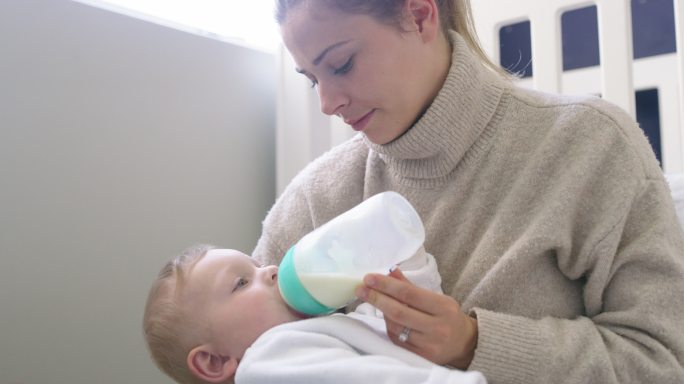 一个可爱的男婴在家被母亲用奶瓶喂养的4k视频片段