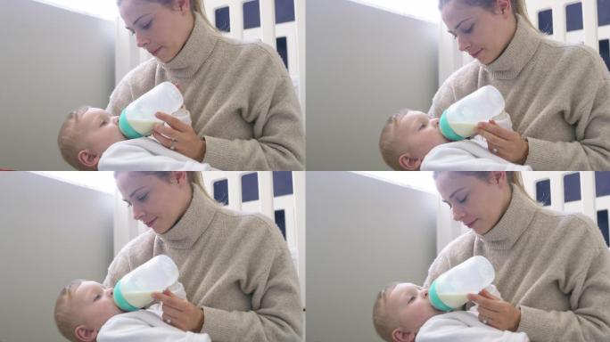 一个可爱的男婴在家被母亲用奶瓶喂养的4k视频片段