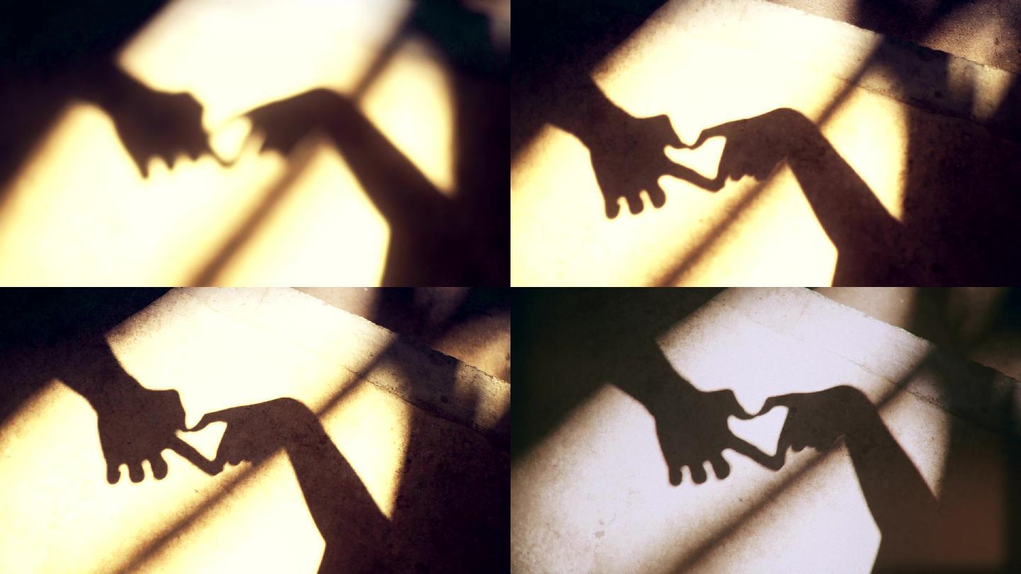情人节用手在地上形成心形阴影的剪影。