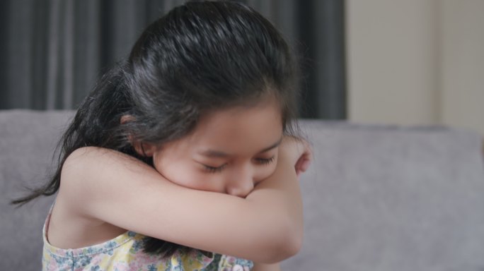 亚洲小孩因流感打喷嚏，用餐巾纸擤鼻涕。她有过敏症。幼小的家中患流感的女孩