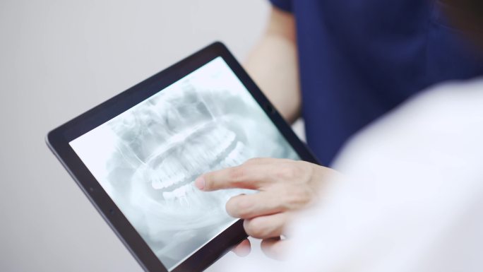 牙医在数字平板电脑中看x光片